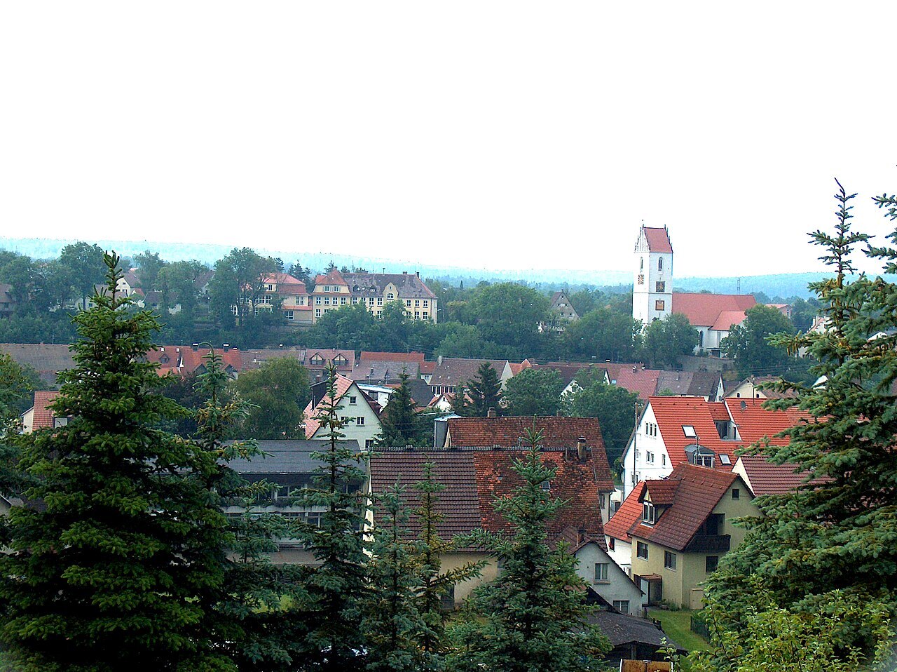 Blick auf Bingen mit Wohngebäuden, einer Kirche mit weißem Turm und im Vordergrund aufragenden Nadelbäumen. Urheber: Roland Nonnenmacher (German Wikipedia) Lizenz: Namensnennung erforderlich (jegliche Nutzung, Weiterverbreitung und Bearbeitung gestattet)